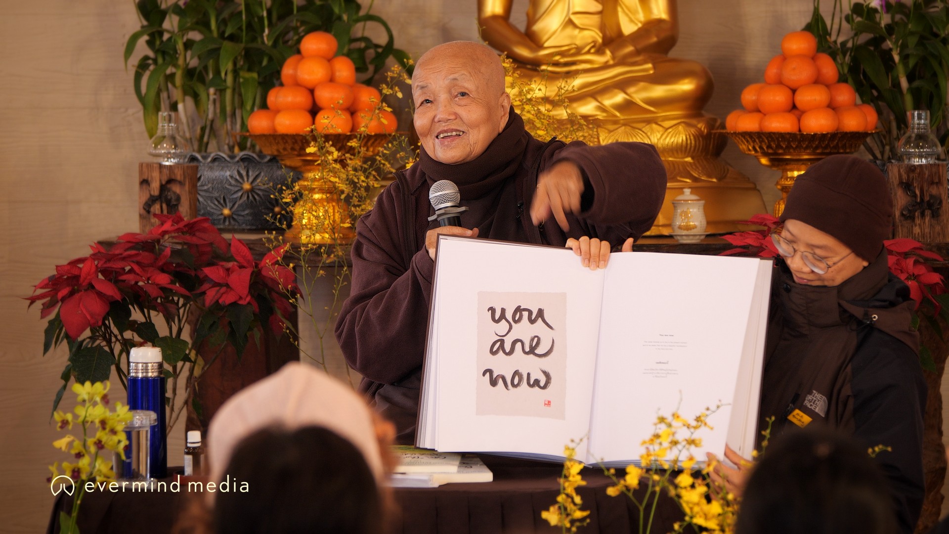 SCCK holds up a calligraphy book with "You Are Now"